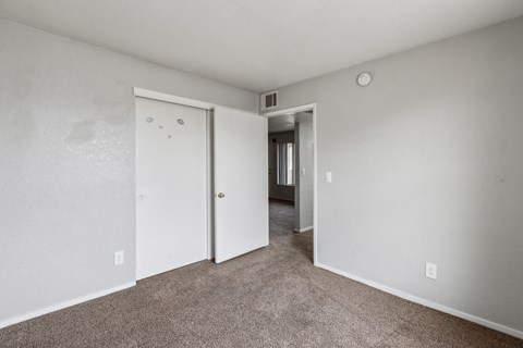 A room with a carpeted floor and two doors.