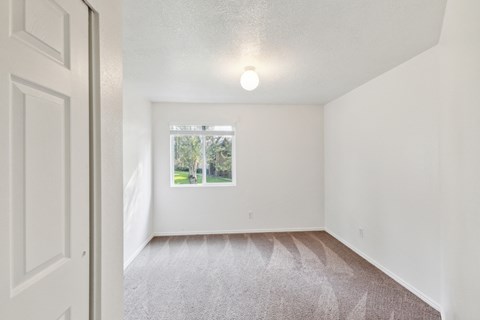 a spacious living room with white walls and a window