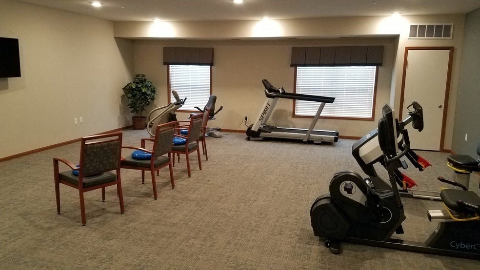 a living room with exercise equipment and a dining room table and chairs
