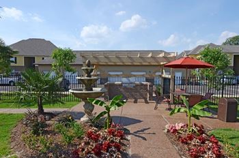 A garden with a fountain and a bench.