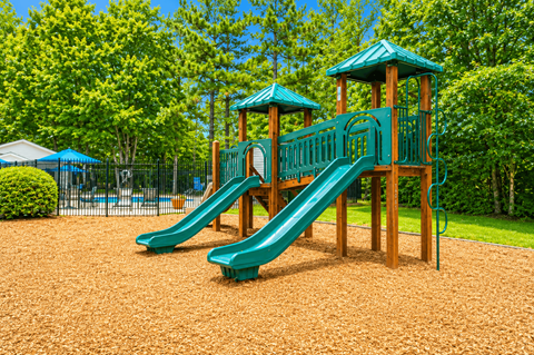 A playground with a green slide and wooden structure.