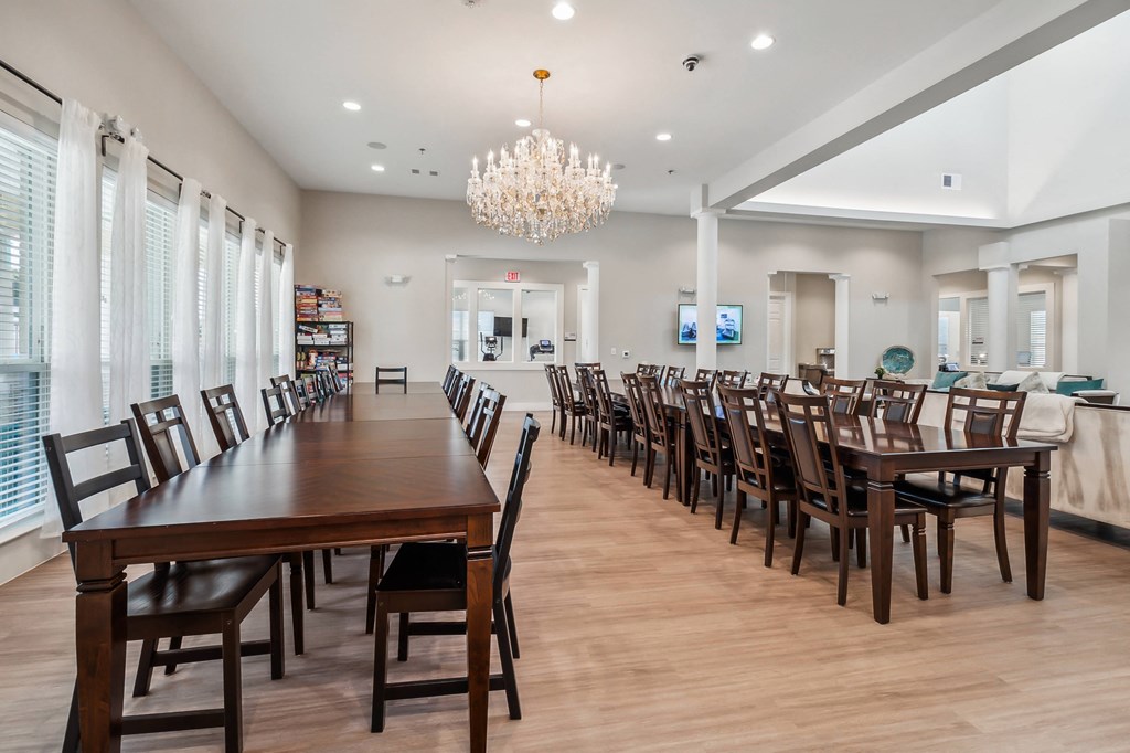 a large dining room with long tables and chairs and a chandelier
