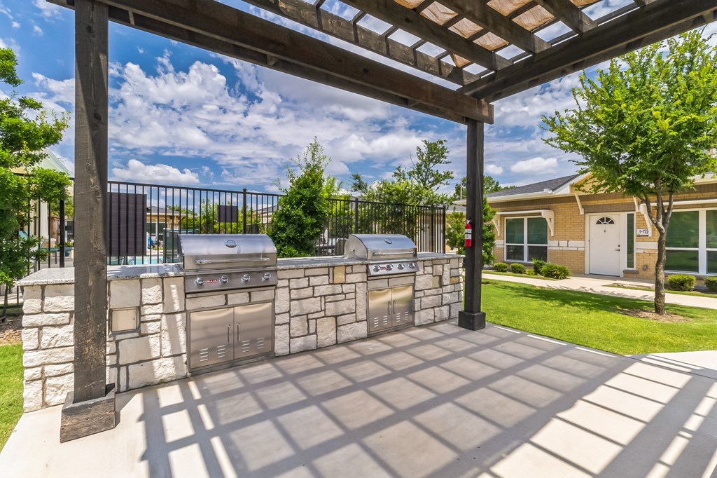 a patio with an outdoor kitchen and a pergola