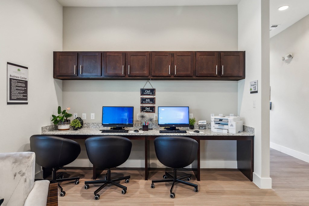 an office with two computers and a desk with chairs