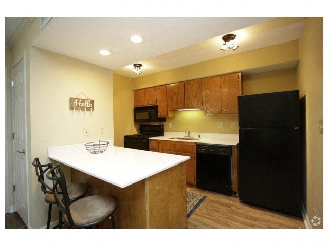 a kitchen with a black refrigerator freezer next to a stove top oven