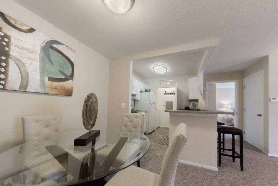 a dining room and kitchen with a glass table and chairs