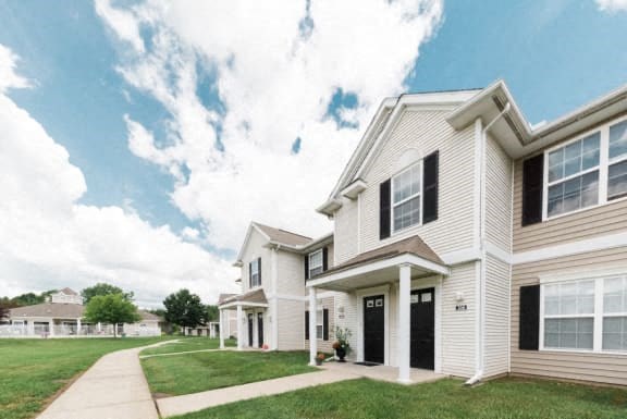 a white house with black shutters and a sidewalk
