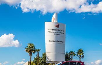 A tall white pillar with a sign on it that says "Hartsfield-Jackson Atlanta International Airport Domestic Terminal".