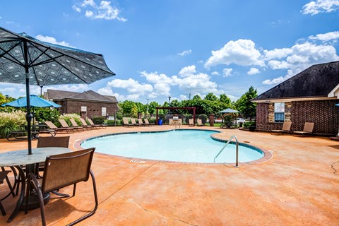 our resort style swimming pool is surrounded by patio furniture and umbrellas