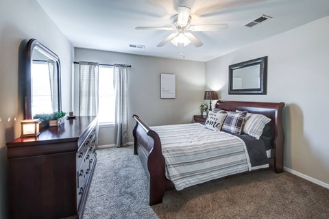 a bedroom with a bed and a dresser and a ceiling fan