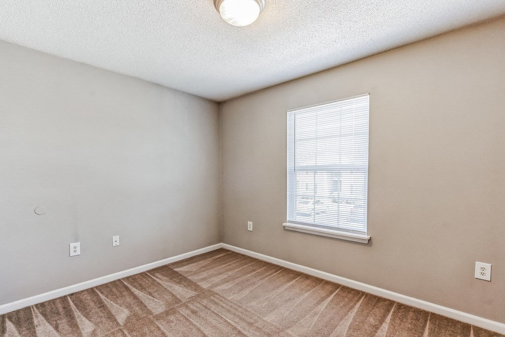 an empty living room with a window and a wooden floor