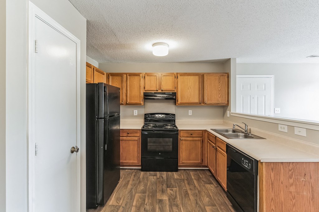 an empty kitchen with wooden cabinets and black appliances