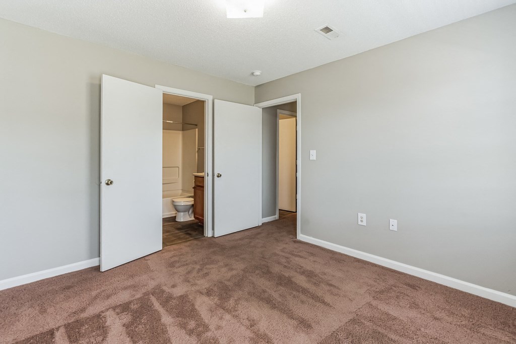 an empty living room with a door leading to a bathroom