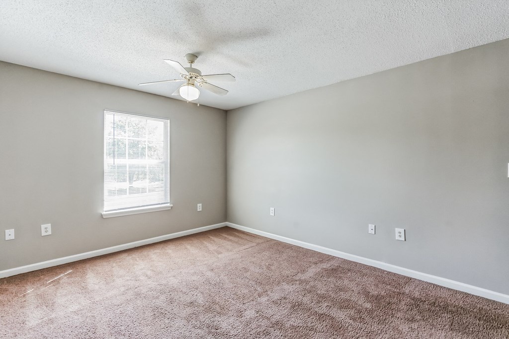 an empty living room with carpet and a ceiling fan