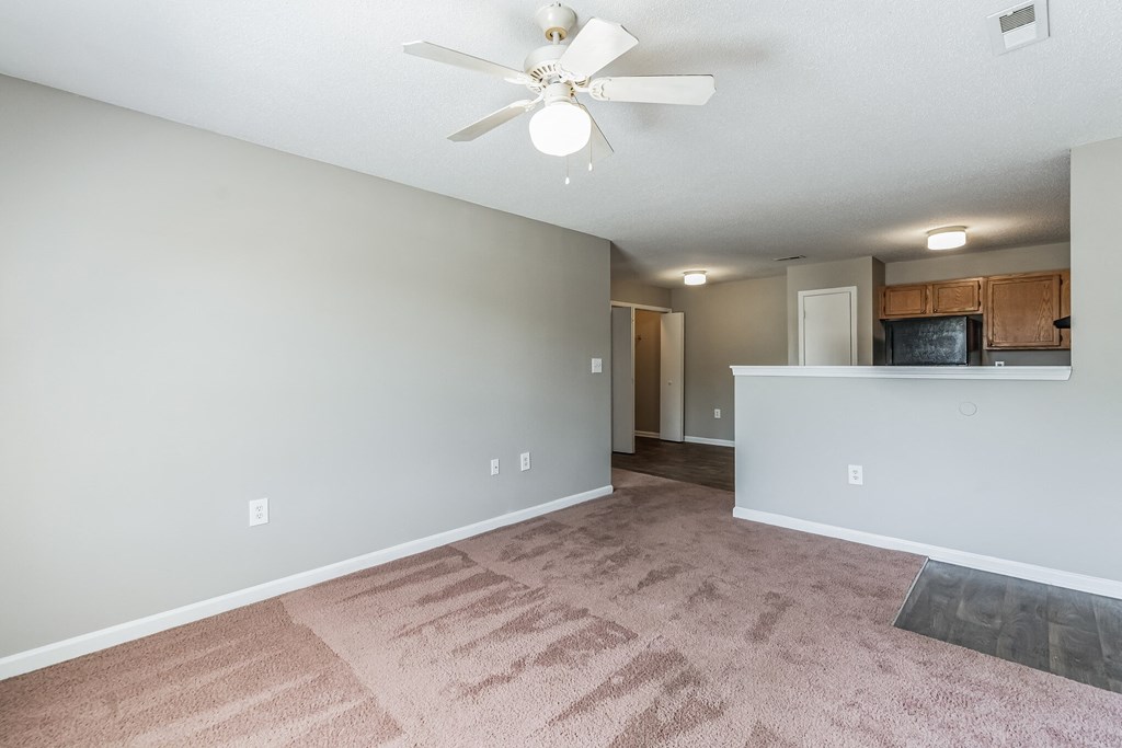 an empty living room and kitchen with a ceiling fan