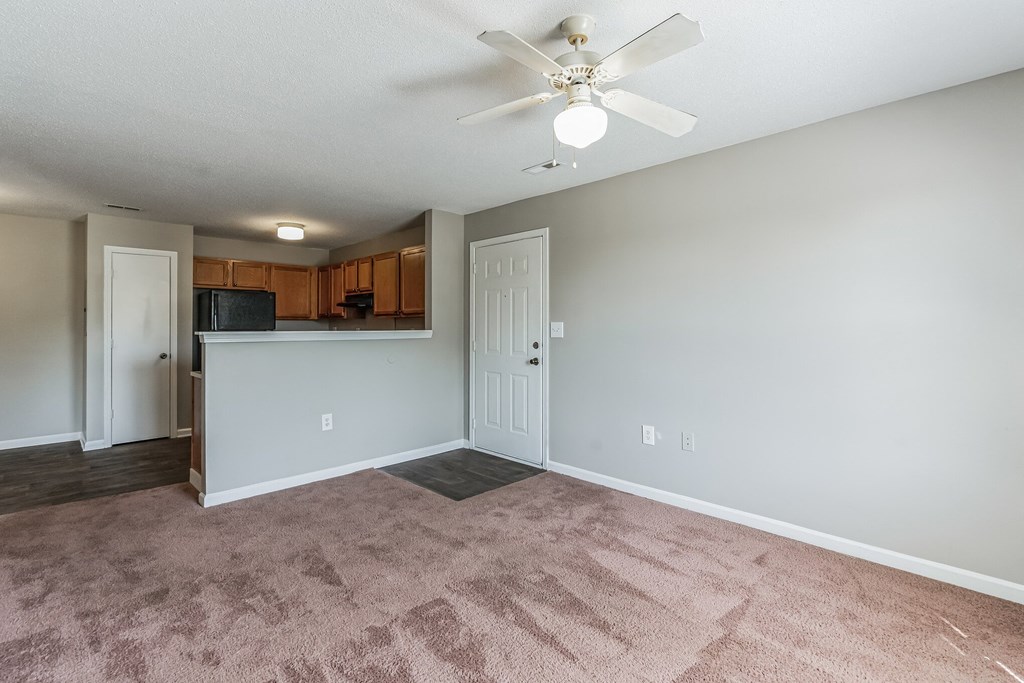 an empty living room with carpet and a ceiling fan
