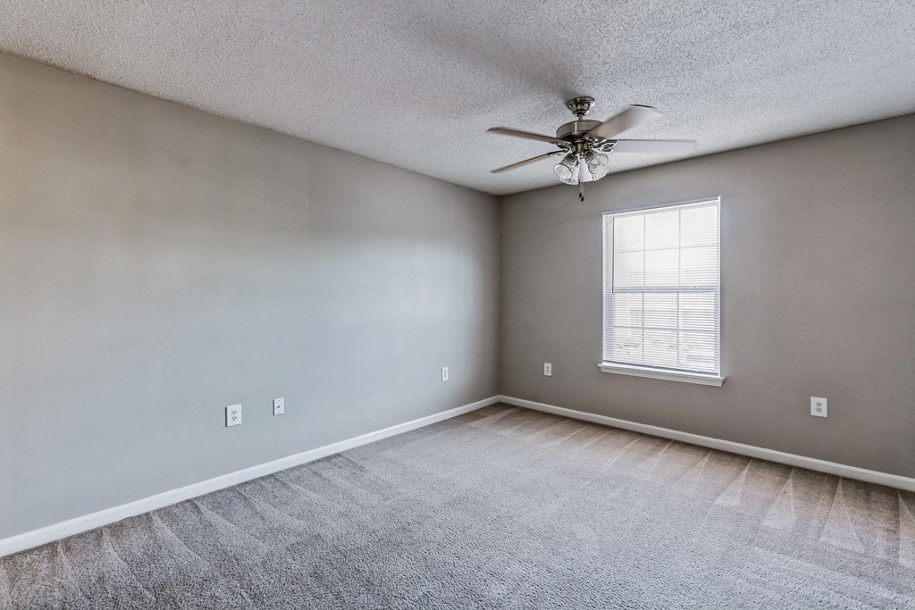 an empty living room with a ceiling fan and a window