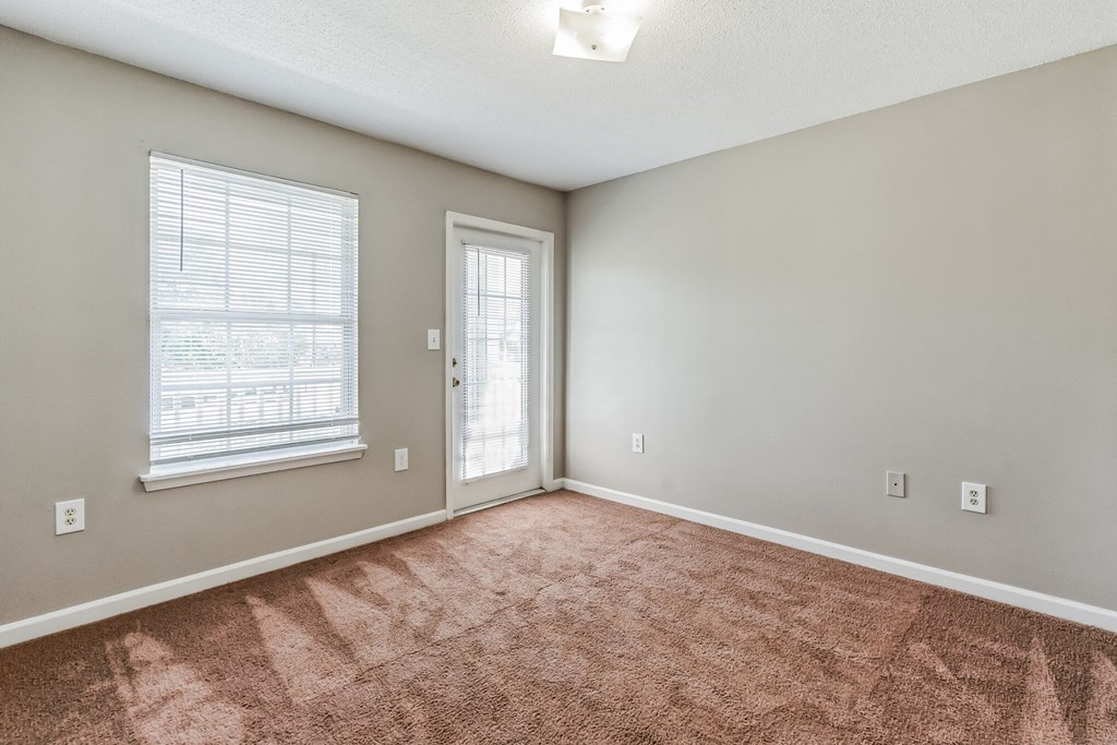 an empty living room with a door and a window