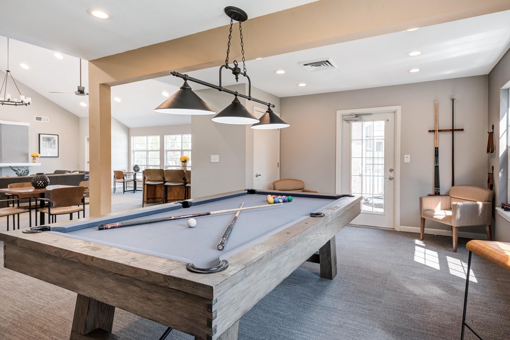 a pool table in the clubhouse of a home with a living room and dining area