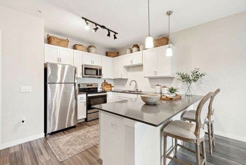 A modern kitchen with a stainless steel refrigerator and white cabinets.