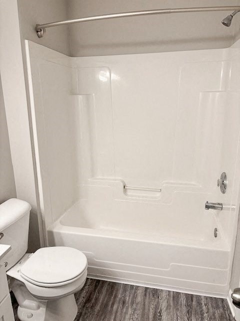 A white toilet sits next to a white bathtub in a bathroom.