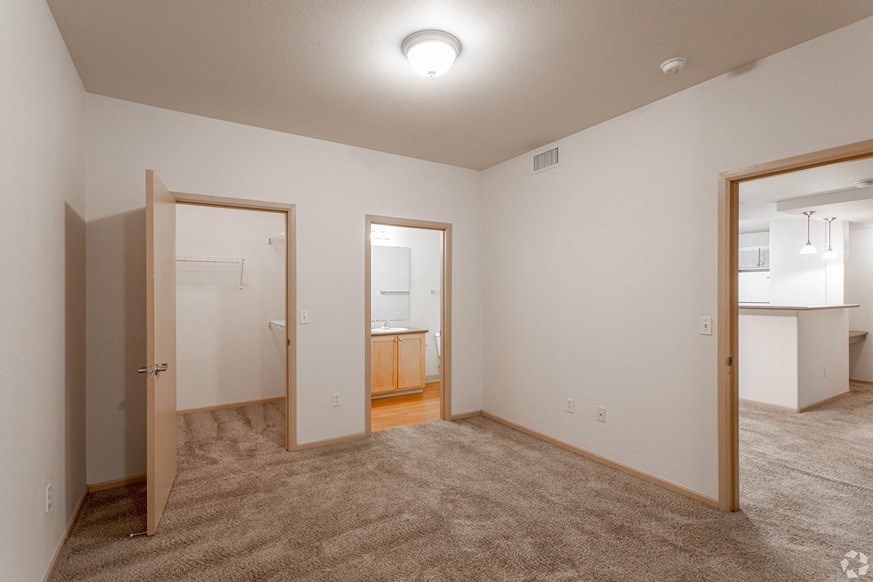 a bedroom with two doors and a bathroom in the background