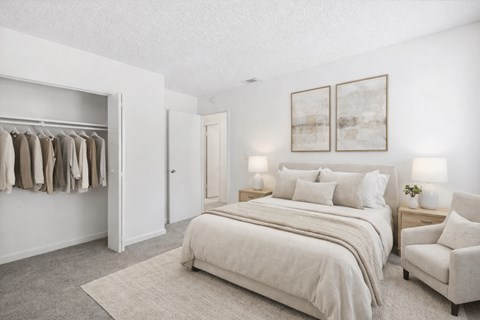 A bedroom with a large bed, a chair, and a wardrobe.