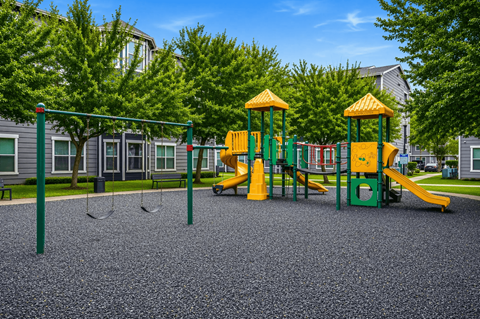 A playground with a yellow and green slide and a green and yellow swing set.