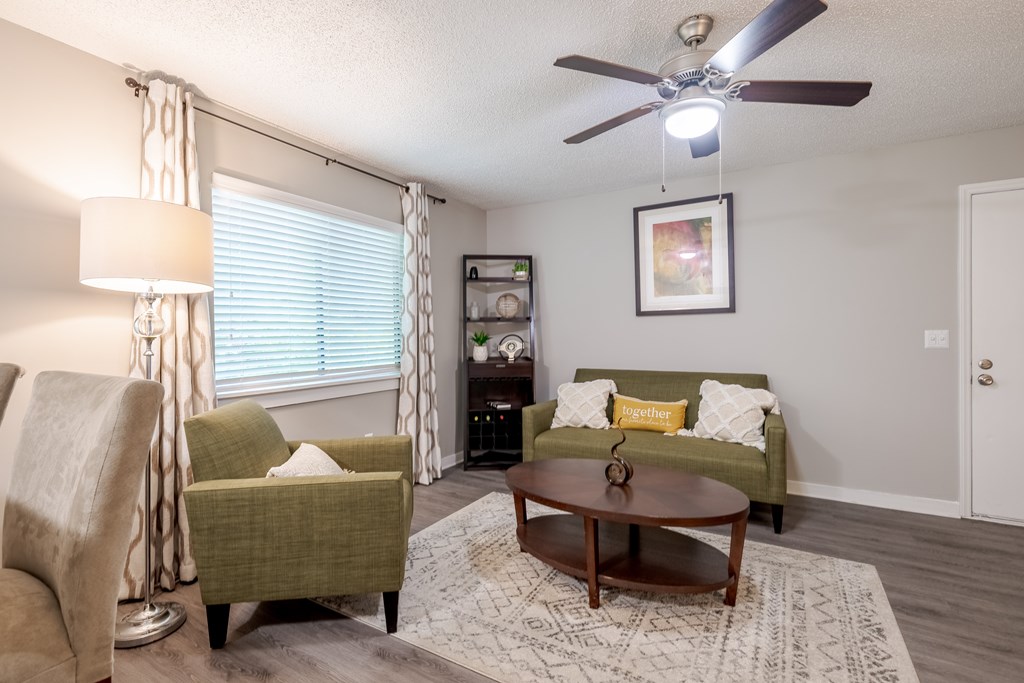 a living room with couches and a table and a ceiling fan