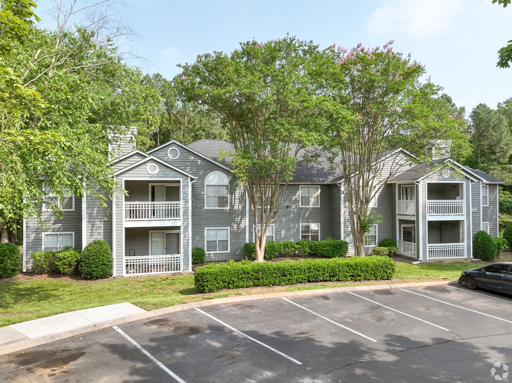 an apartment building with a parking lot and trees at Delta Crossing, Charlotte, North Carolina
