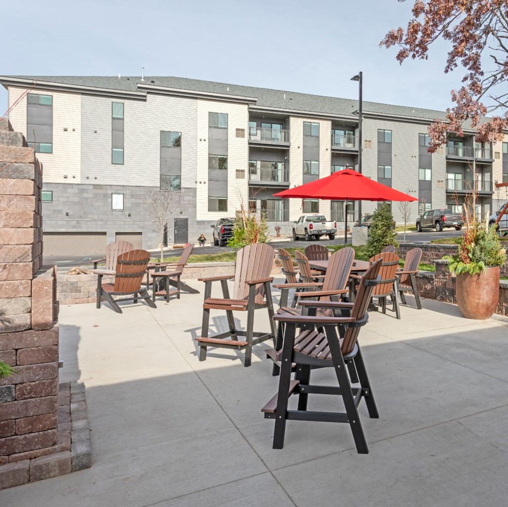 a patio with chairs and an umbrella in front of an apartment building
