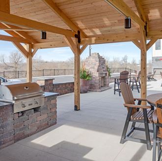 a covered patio with a barbecue grill and a table with chairs