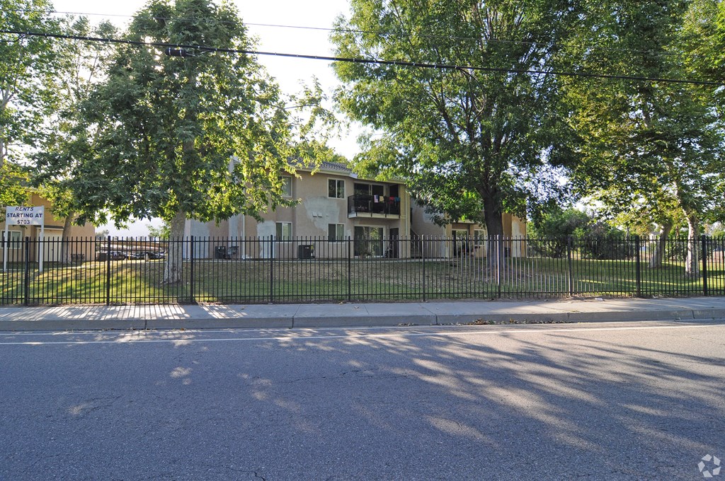 a house with a fence and trees in front of it