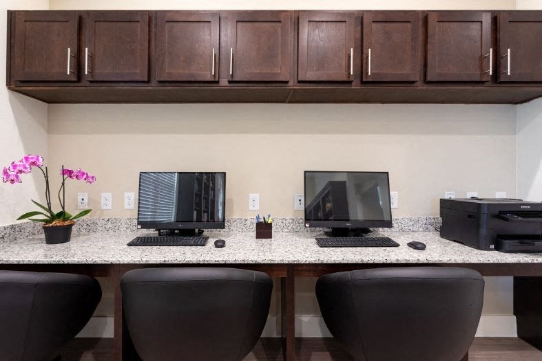 two computers sitting on a counter with chairs