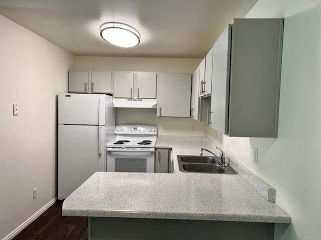 a white kitchen with a sink and a refrigerator