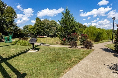 a park with a sidewalk and grass and trees