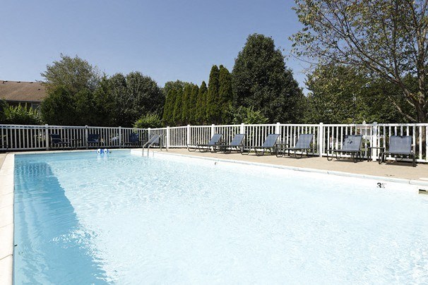 a swimming pool with chairs and a fence around it