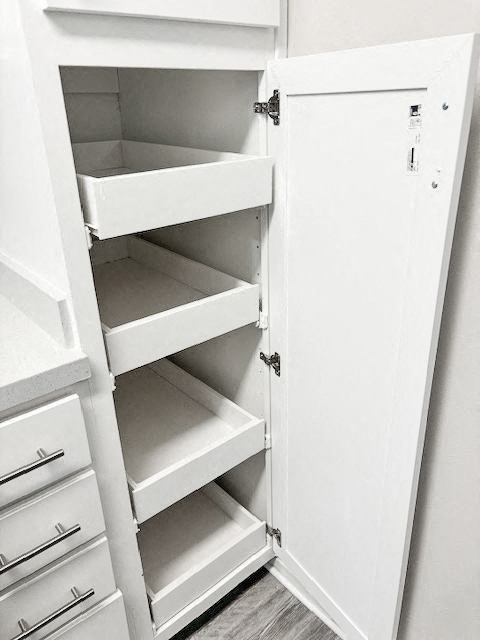 A white kitchen pantry with an open door.
