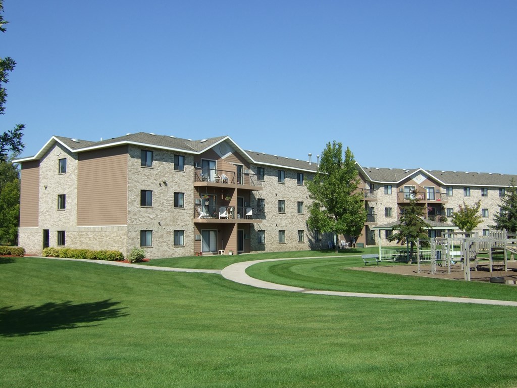 an exterior view of an apartment building with a green yard