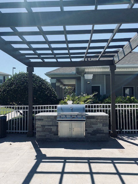 a patio with a grill and a pergola
