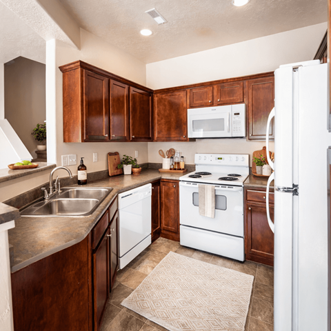 A kitchen with white appliances and wooden cabinets.