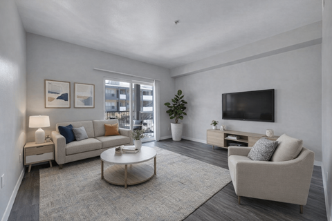 A living room with a white couch, a white coffee table, and a television on a wooden stand.