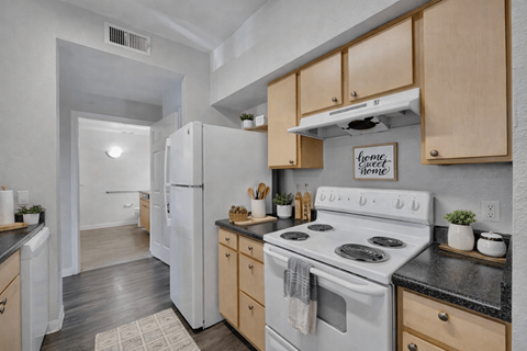 A kitchen with a white stove and wooden cabinets.