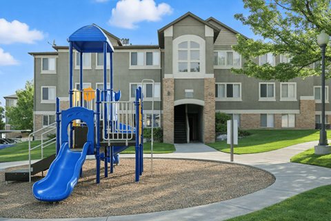 A playground with a blue slide in front of a building. at Diamond Fork Apartments, Spanish Fork, 84660