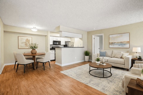 A living room with a white couch and a dining table with chairs.