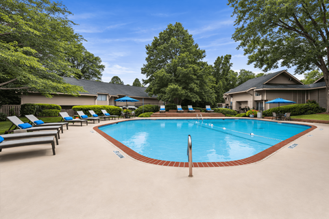 A swimming pool surrounded by lounge chairs and trees.