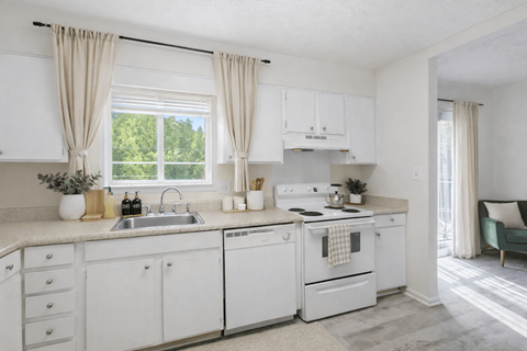 A white kitchen with a window and curtains.