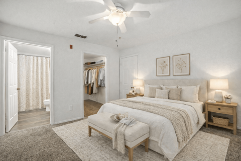 A bedroom with a large bed, a bench, and a ceiling fan.