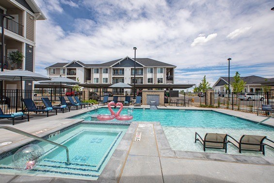 A swimming pool with a slide and chairs around it. at Connect at First Creek Apartments, Denver, CO