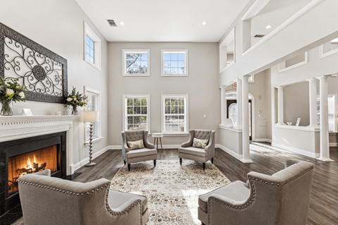 A living room with a fireplace and grey chairs.